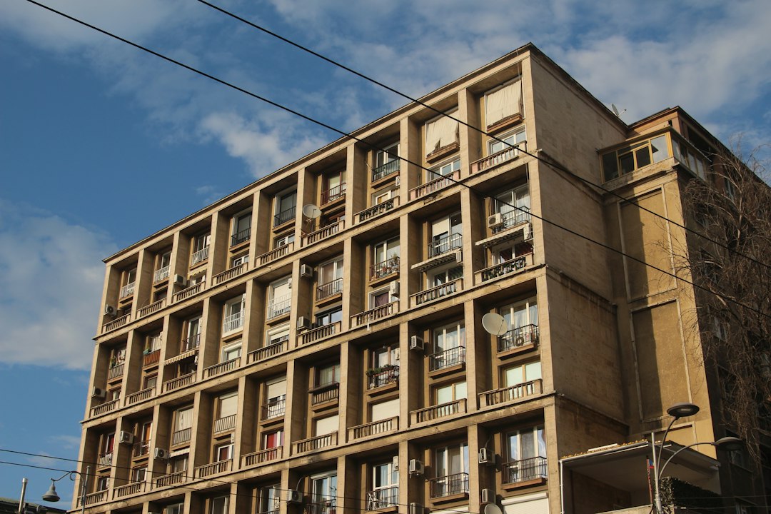 Bloc de apartamente în România cu simbol de calculator și grafic de creștere a impozitului, ilustrând reforma fiscală din 2027