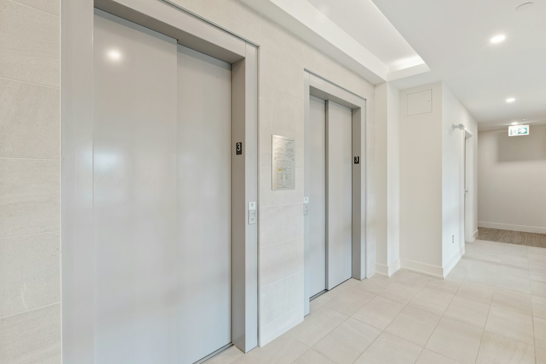 Cabină de lift oprită între etaje într-un bloc de locuințe, cu panoul de butoane și butonul de alarmă iluminat