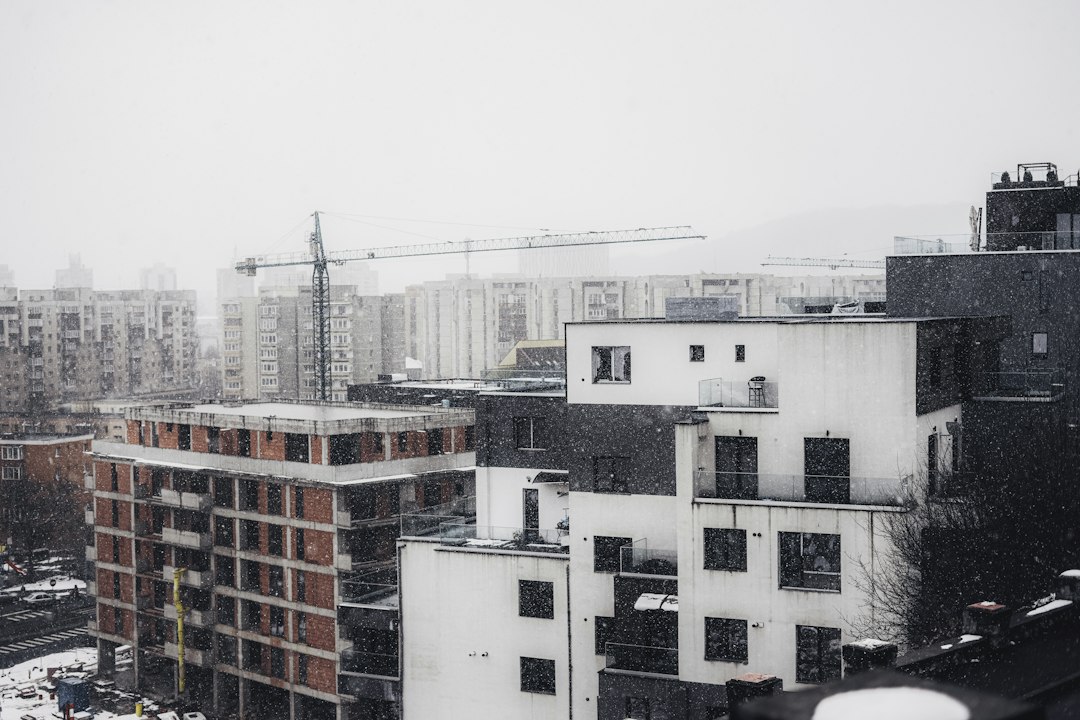 Bloc de apartamente pe jumătate anvelopat cu polistiren, cu fațada veche vizibilă pe una din laturi, într-o dimineață de iarnă