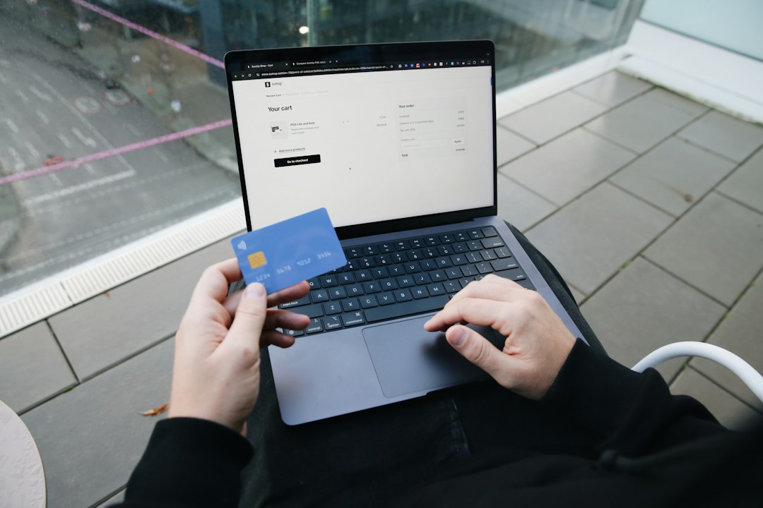 Administrator de bloc verifică pe laptop un e-mail cu o factură de furnizor și compară IBAN-ul cu cel din contract