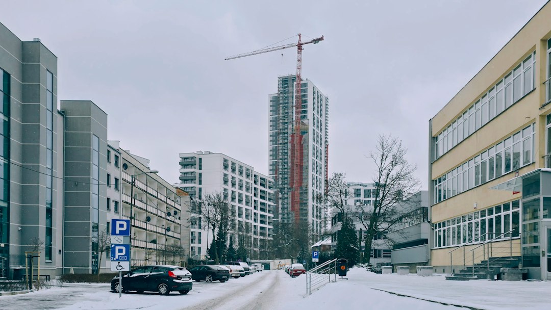 Schelă acoperită cu plasă de protecție pe fațada unui bloc de apartamente în zi friguroasă de iarnă, cu zăpadă pe trotuar