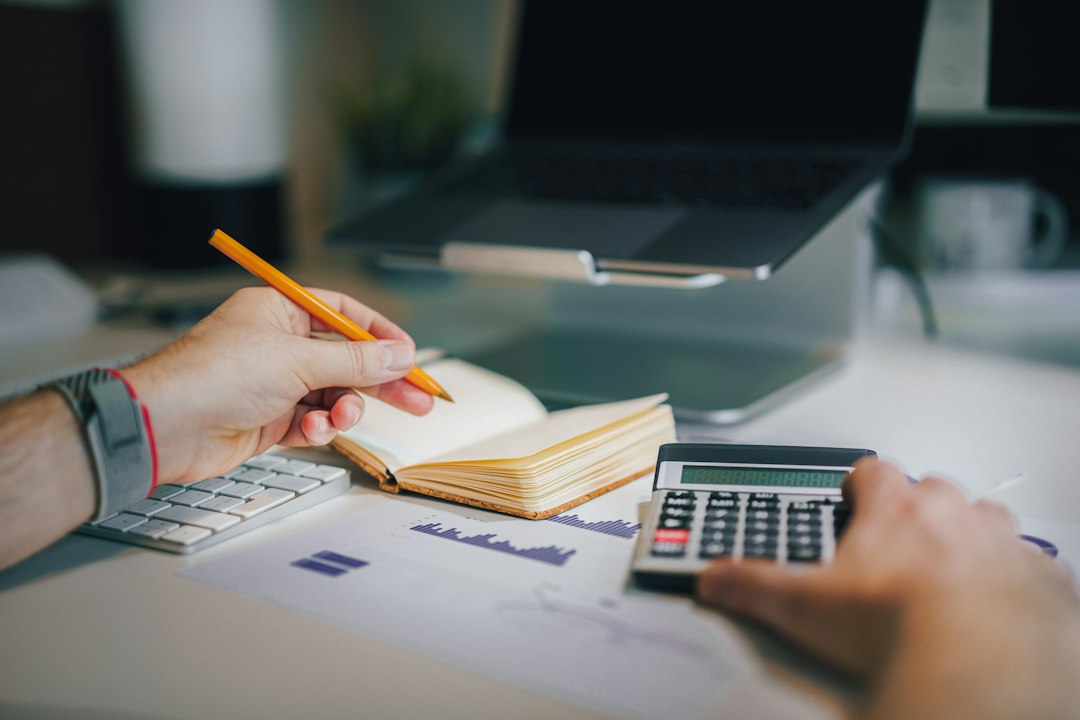 Administrator de bloc care verifică execuția bugetară a asociației de proprietari pe hârtie și pe laptop, în decembrie, înainte de adunarea generală de rectificare