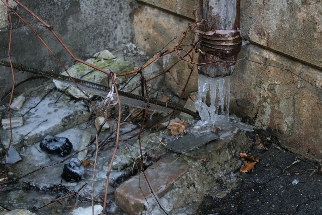 Apometru și țeavă de apă acoperite de gheață într-o nișă neizolată de pe casa scării unui bloc, iarna